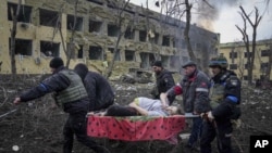 Ukrainian emergency employees and volunteers carry an injured pregnant woman from the damaged by shelling maternity hospital in Mariupol, Ukraine, Wednesday, March 9, 2022. (AP Photo/Evgeniy Maloletka)