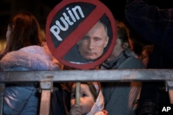 Seorang gadis memegang plakat bergambar Presiden Rusia Vladimir Putin pada protes terhadap invasi Rusia ke Ukraina di Tel Aviv, Israel, 5 Maret 2022. (Foto: AP)