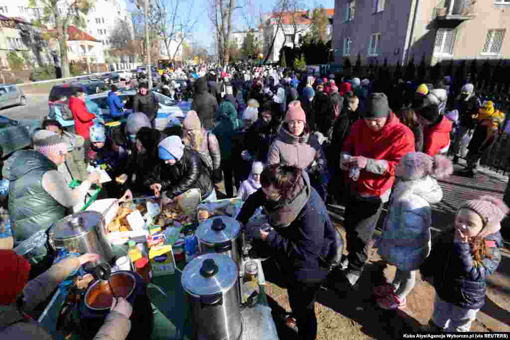 Refugees eat as they wait in front of the Ukrainian consulate in Warszawa, Poland, March 10, 2022. 