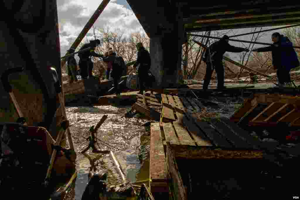 Civilians in Irpin escape from the battles through an improvised path created alongside a bombed bridge by Ukrainian forces in Ukraine, March 8, 2022. (Yan Boechat/VOA) 
