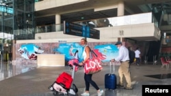 Turis asing membawa barang bawaan mereka setibanya di Bandara Internasional I Gusti Ngurah Rai, saat pemerintah setempat memulai hari pertama uji coba 'bebas karantina', di tengah pandemi COVID-19 di Bali, 7 Maret 2022. (REUTERS/Sultan Anshori)