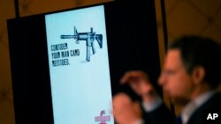 An image of the advertising used for an AR-15-style rifle is displayed while attorney Josh Koskoff speaks during a news conference in Trumbull, Conn., Tuesday, Feb. 15, 2022. (AP Photo/Seth Wenig)