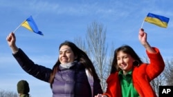 两位女士在乌克兰的克拉马托尔斯克举着乌克兰国旗，度过“团结日”。(2022年2月16日)