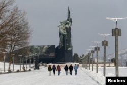 FILE - People walk towards a monument to the Liberators of Donbas in the rebel-held city of Donetsk, Ukraine, Jan. 27, 2022.