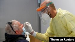 A health worker takes a swab sample from a man to test for the coronavirus disease (COVID-19), at the Fiumicino Airport in Rome