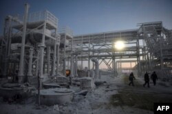 Orang-orang berjalan melalui ladang Utrenneye, basis sumber daya untuk proyek Novatek's Arctic LNG 2, yang terletak di Semenanjung Gydan di garis pantai Laut Kara di lingkaran Arktik, sekitar 2.500 km dari Moskow, 30 November 2021. (Foto: AFP)