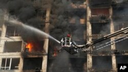 15일 우크라이나 수도 크이우에서 소방관들이 러시아의 포격으로 건물에 난 불을 끄고 있다.