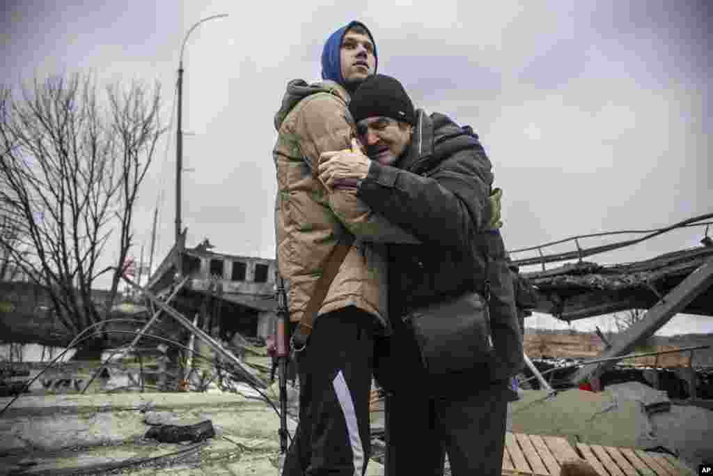 A Ukrainian Territorial Defense Forces member hugs a resident who leaves his home town following Russian artillery shelling in Irpin, on the outskirts of Kyiv, March 9, 2022.