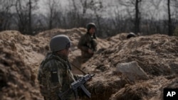 Ukrainian servicemen stand in trenches at a position north of the capital Kyiv, Ukraine, March 29, 2022. 