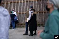 FILE - A woman from Ukraine stands at the border with her fiance from the United States as she waits to ask for asylum, in Tijuana, Mexico, March 10, 2022.