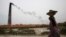 FILE - Smoke emits from chimney as a Bangladeshi female worker carries clay at a brick field at Amin Bazar, outskirts of Dhaka, Bangladesh, Thursday, May 14, 2009.