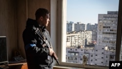 Un policier de Kiev monte la garde depuis les étages d'un immeuble.