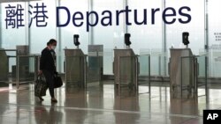 FILE - A woman walks through the airport in Hong Kong, Feb. 18, 2022. Hong Kong's leader Carrie Lam on March 21, 2022, said that the city would lift flight bans on countries including Britain and the U.S.