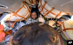Expedition 66 crew members Mark Vande Hei of NASA (L), cosmonauts Anton Shkaplerov (C), and Pyotr Dubrov of Roscosmos, are seen inside their Soyuz MS-19 spacecraft after is landed in a remote area near the town of Zhezkazgan, Kazakhstan, March 30, 2022.