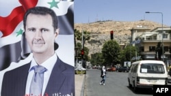 FILE - A large sign bearing the portrait of Syria's President Bashar al-Assad, with text in Arabic below reading “we have chosen you for we have loved you,” is displayed along Abo Romaneh street in the capital Damascus on May 10, 2021, ahead of presidential elections.
