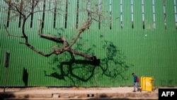 A man walks past a fence of a construction site along a street in New Delhi, India, March 9, 2022.