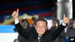 FILE - Lee Jae-myung, the presidential candidate of the ruling Democratic Party, raises his hands during a presidential election campaign in Seoul, South Korea, March 8, 2022.
