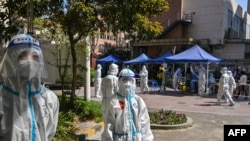 Para petugas dan relawan yang memakai alat pelindung diri (APD) mengawasi distrik Jing' an di Shanghai, China di mana pemerintah menerapkan lockdown dan karantina bagi mereka yang positif COVID-19, 4 April 2022. 