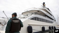 Seorang petugas sipil berdiri di dekat kapal pesiar "Tango" di Palma de Mallorca, Spanyol, Senin 4 April 2022. (AP/Francisco Ubilla)