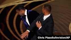 FILE - Will Smith, right, hits presenter Chris Rock on stage at the Oscars, at the Dolby Theatre in Los Angeles, March 27, 2022.