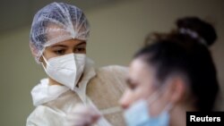 FILE - A medical worker administers a nasal swab to a patient at a COVID-19 testing center in Les Sorinieres, France, June 23, 2022. 