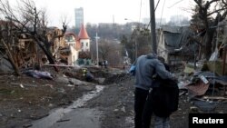A local resident embraces his son as they stand next to a site of a Russian missile strike in Kyiv, Ukraine, Dec. 31, 2022. 