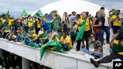 Protesting supporters of Brazil's former President Jair Bolsonaro stand on the roof of the National Congress building after storming it, in Brasilia, Brazil, Jan. 8, 2023.