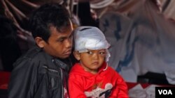 Salmatu Sad'ah (kanan) bersama ayahnya, Dede berada di posko pengobatan RSUD Sayang. Tempat tinggal Dede di Desa Gasol, Cianjur rata dengan tanah akibat gempa berkekuatan 5.6 magnitudo pada Senin (21/11) siang. (VOA/Indra Yoga)