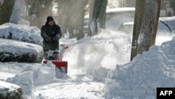 ARCHIVES - Un homme dégage un trottoir à l'aide d'une souffleuse dans le Bronx le 3 janvier 2014 à New York.