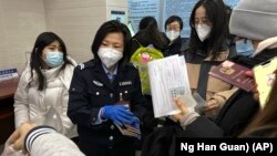 An officer collects passports from residents for renewal and re-applications at a community police station in Beijing, Wednesday, Dec. 28, 2022. (AP Photo/Ng Han Guan)