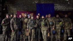 Nan foto sa a ke Biwo Prezidans Ikren nan pataje ak lapres, solda Ikrenyen yo poze pou yon foto ak Prezidan Volodymyr Zelenskyy (mitan) pandan yon vizit li te fe nan Sloviansk, rejyon Donbas, Ikren, 6 Desanm, 2022. 