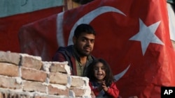 A Syrian migrant man and daughter stand in front of their shelter in Ulus district, the old part of Turkish capital Ankara, Turkey, Oct. 23, 2022. 