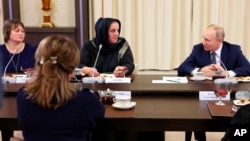 Russian President Vladimir Putin listens to Zharadat Agueva of the Chechen Republic during a meeting with mothers of personnel serving in the action against Ukraine, at the Novo-Ogaryovo presidential residence in suburban Moscow, Nov. 25, 2022.