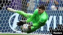 Kiper Kroasia Dominik Livakovic menyelamatkan gawangnya dari tendangan penalti Takumi Minamino (Jepang) dalam pertandingan Babak 16 Besar Sepak Bola Piala Dunia FIFA Qatar 2022 di Stadion Al Janoub, Al Wakrah, Qatar, 5 Desember 2022 (REUTERS/Marko Djurica)