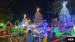 Warga bersantai di depan barisan pohon natal yang berdiri di halaman Gereja Kristen Sulawesi Tengah (GKST) Jemaat Ebenhaezer, Kelurahan Ranononcu, Poso Kota Selatan, Kamis (22 Desember 2022) (Foto : VOA/Yoanes Litha)