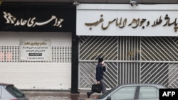 Seorang pria berjalan melewati toko-toko yang tutup di sepanjang jalan Satarkhan di ibu kota Iran, Teheran, 5 Desember 2022. (ATTA KENARE / AFP)