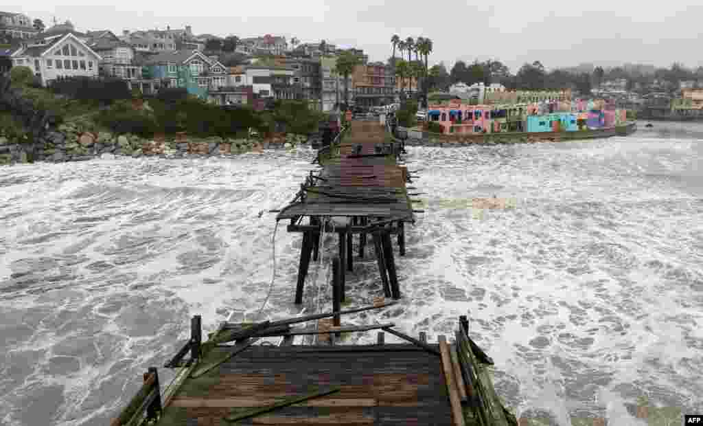 This aerial view shows a damaged pier is split in Capitola, California, Jan. 9, 2023.&nbsp;A massive storm called a &quot;bomb cyclone&quot; by meteorologists has arrived and is expected to cause widespread flooding throughout the state.&nbsp;