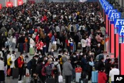 “春运”在如同海啸般蔓延的新冠感染爆发中拉开帷幕。广东深圳南站大厅内，旅客们人们带着口罩和行李，熙熙攘攘挤满大厅，等待买票和登车。本照片由新华社发布，美联社提供。