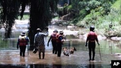 Rescue workers search the waters of the Jukskei River in Johannesburg, South Africa, Dec. 4, 2022, after a deadly flash flood swept through the area.