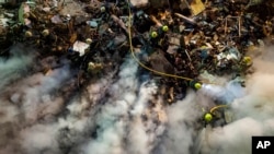 Emergency workers clear the rubble after a Russian rocket hit a multistory building leaving many people under debris in the southeastern city of Dnipro, Ukraine, Jan. 14, 2023.