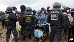 Seorang demonstran di kursi roda ikut serta dalam protes di dekat tambang terbuka lignit Garzweiler, di Desa Luetzerath dekat Erkelenz, Jerman, 14 Januari 2023. (Foto: via AP)