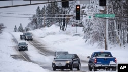 Mobil perlahan-lahan berjalan melalui persimpangan jalan di di Duluth, Minnesota utara, Kamis, 15 Desember 2022. (AP Photo/Holden Law)