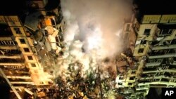 Emergency workers clear the rubble after a Russian rocket hit a multistory building leaving many people under debris in the southeastern city of Dnipro, Ukraine, Jan. 14, 2023. 