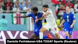 Le milieu de terrain des États-Unis d'Amérique Yunus Musah (en bleu) lutte pour le ballon contre le milieu de terrain iranien Mehdi Torabi (No. 16) le 29 novembre 2022 à Doha, au Qatar.