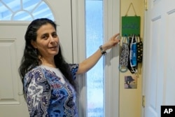 Koloud "Kay" Tarapolsi pokazuje na držač za maske koji je napravila njena kćerka i na kojem je na arapskom napisana fraza "Za vaše zdravlje", u njenom domu u Redmondu, u državi Washington. (Foto: AP/Ted S. Warren)