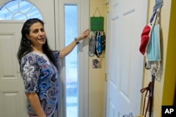 FILE -- Koloud "Kay" Tarapolsi points to a mask holder made by her daughter that has the phrase "To Your Health" written in Arabic on it, at her home in Redmond, Washington.