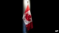 FILE - The Canadian flag displayed at the Embassy of Canada in Washington, June 20, 2019. Canada is is making it possible for the first time for spouses and working-age children of temporary foreign workers to work legally in the country themselves.