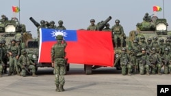 Tentara mengibarkan bendera Taiwan setelah menggelar latihan peningkatan kesiapsiagaan yang mensimulasikan pertahanan melawan gangguan militer Beijing, di Kota Kaohsiung, Taiwan pada Rabu, 11 Jan 2023. (Foto: AP)
