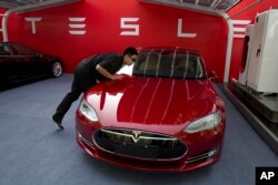 Seorang pekerja membersihkan sedan Tesla Model S pada Rabu, 17 Oktober 2018. (Foto: AP)