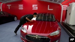 Seorang pekerja membersihkan sedan Tesla Model S di Beijing pada Rabu, 17 Oktober 2018. (Foto: AP)